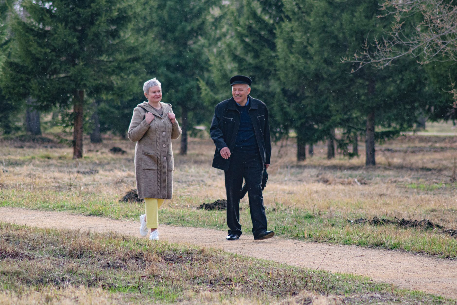 A carer walking beside an older man on a residential street